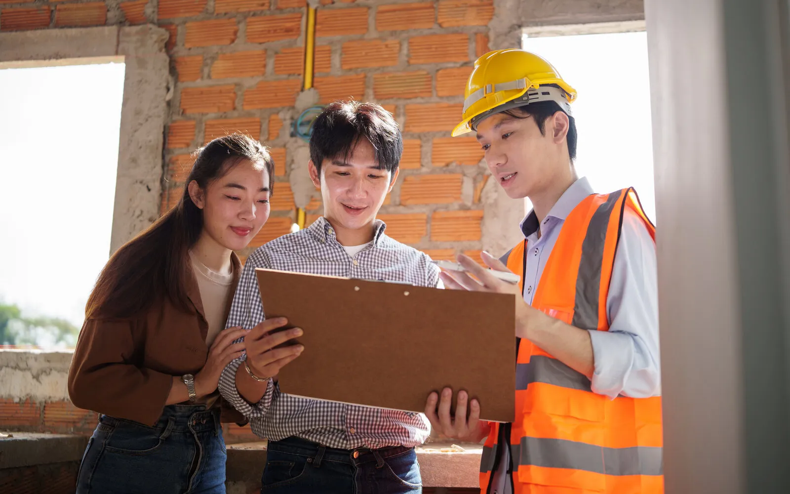 Contractor reviewing project documents with a client at a residential building site, illustrative photo