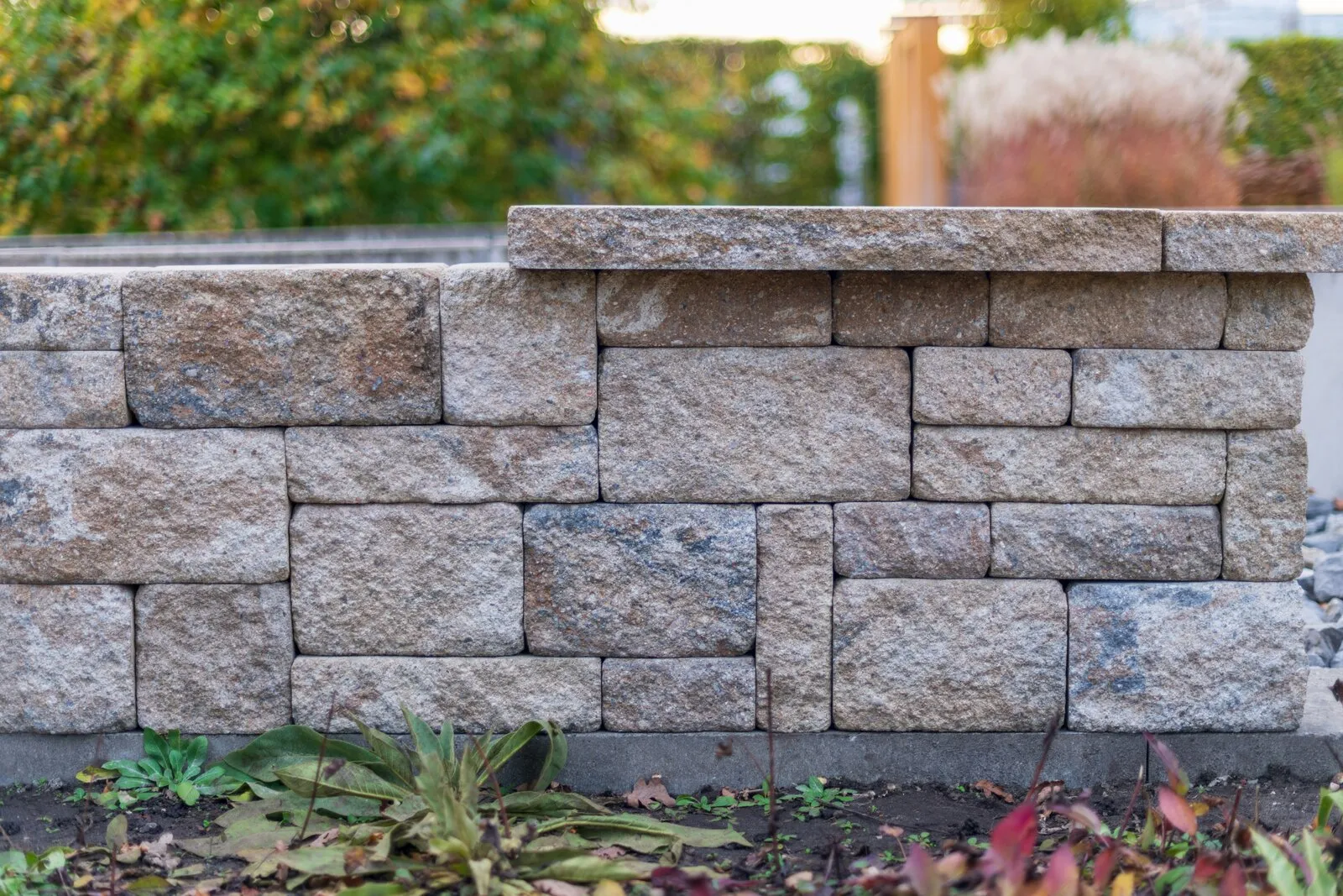 Stacked segmental retaining wall blocks in a landscaped garden, illustrative photo